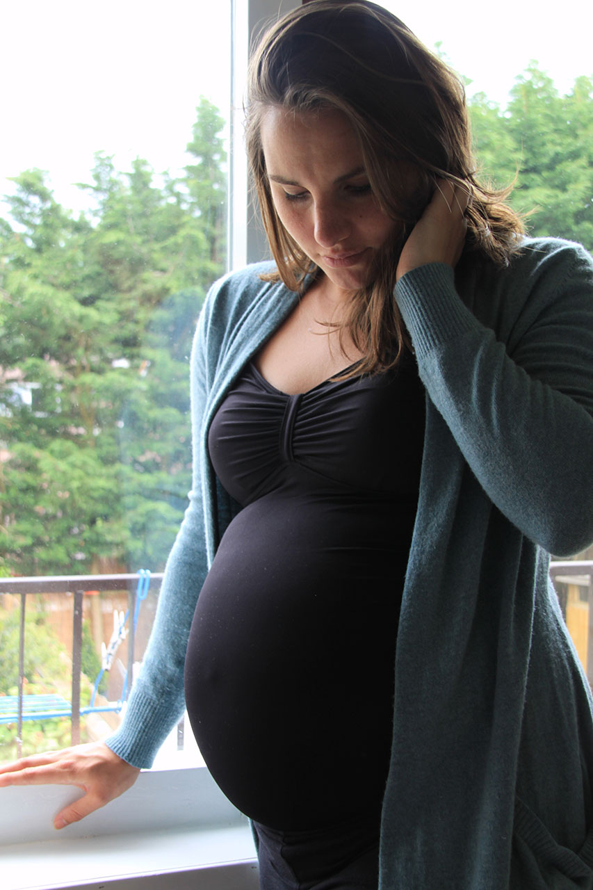 Zwangere vrouw kijkt naar haar buik.