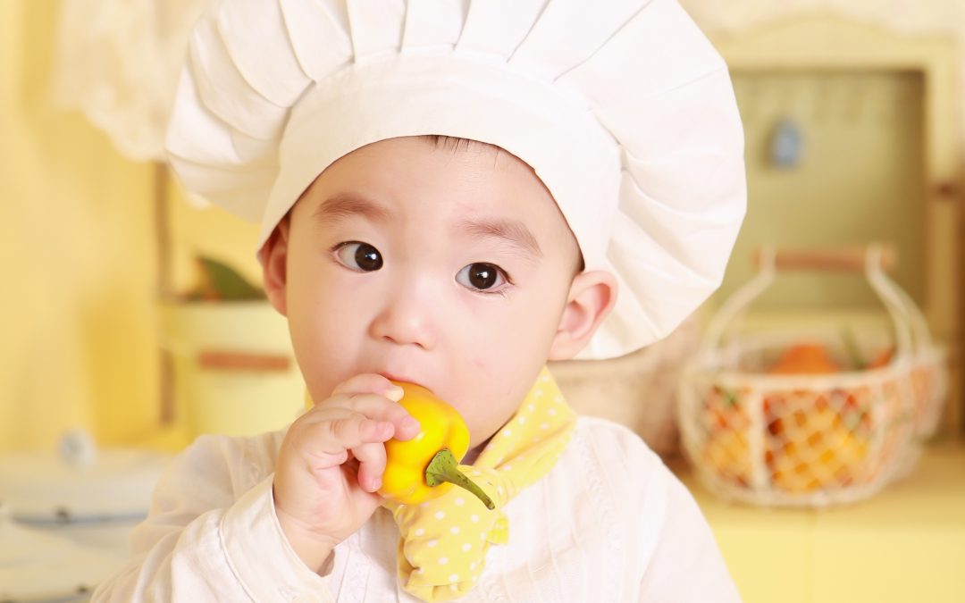 Baby met kookmuts in keuken